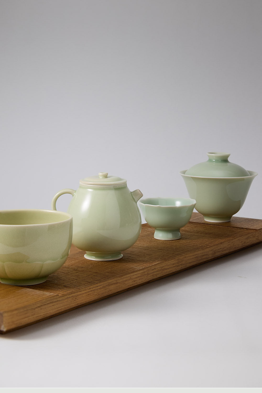 A complete ceramic tea set from the RouseClay collection, featuring an Ou kiln celadon tea cup, a matching Gaiwan, and a handmade celadon teacup and teapot.
