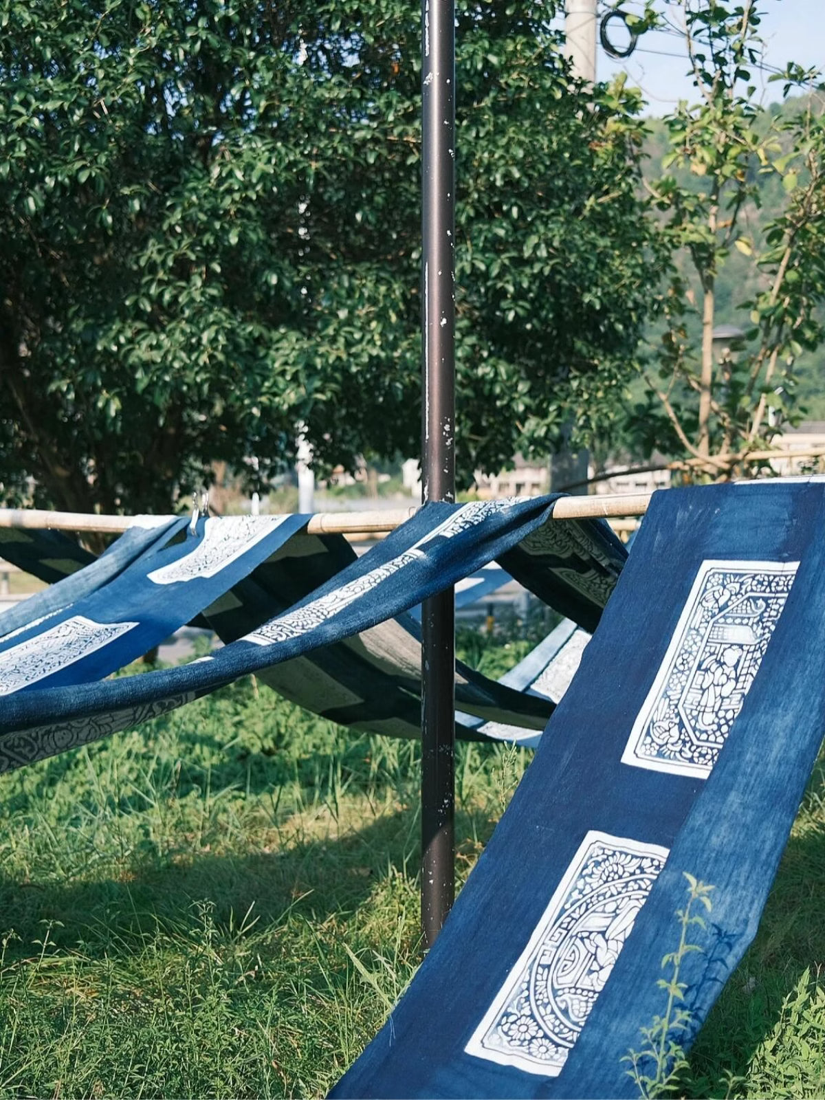 Hand-dyed indigo fabric with traditional resist patterns drying in shade