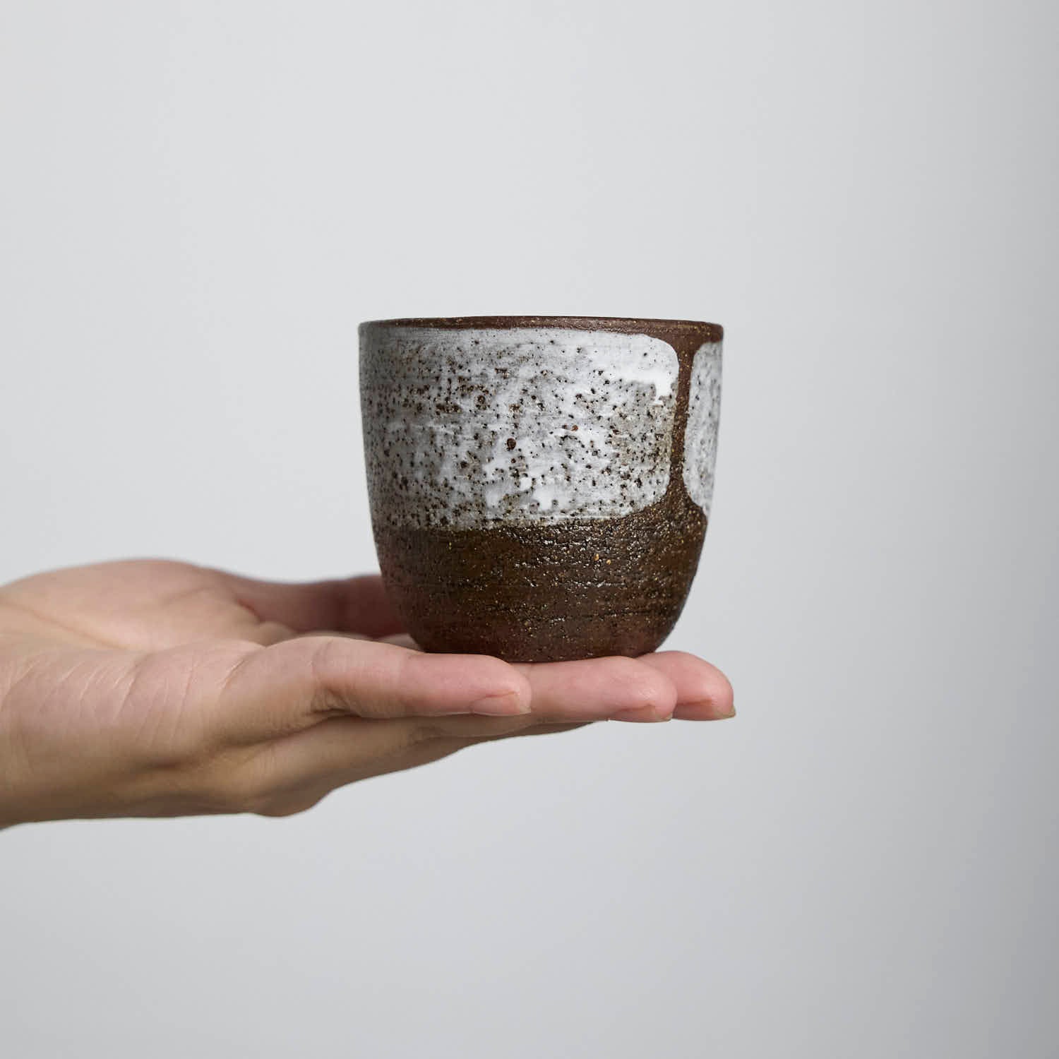 Handcrafted stoneware cup with white slip glaze overlay, wabi-sabi style ceramic teacup made from dark iron clay.