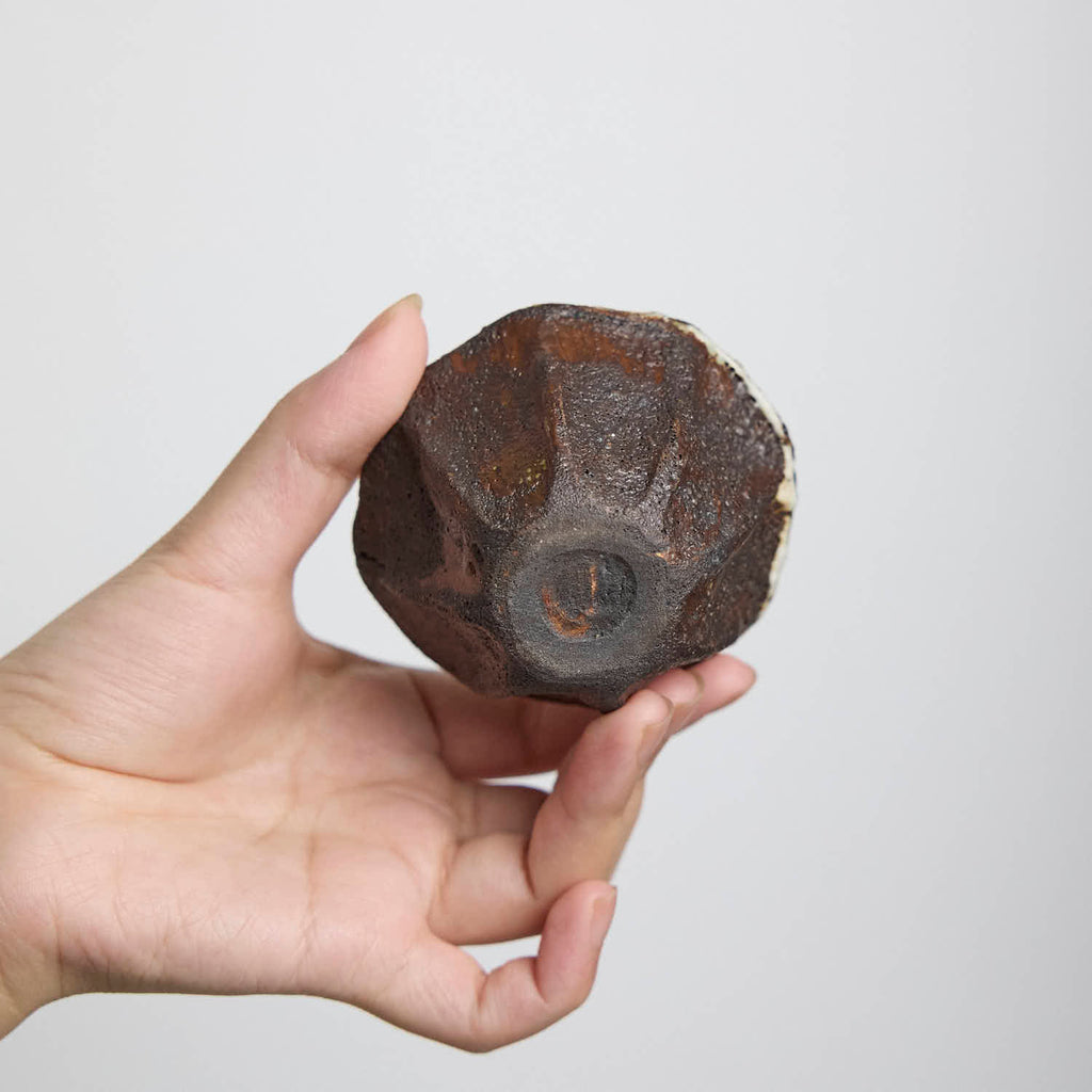Handbuilt wood-fired clay cup with white slip finish, wabi-sabi style ceramic teacup showing natural ash glaze and irregular rim.