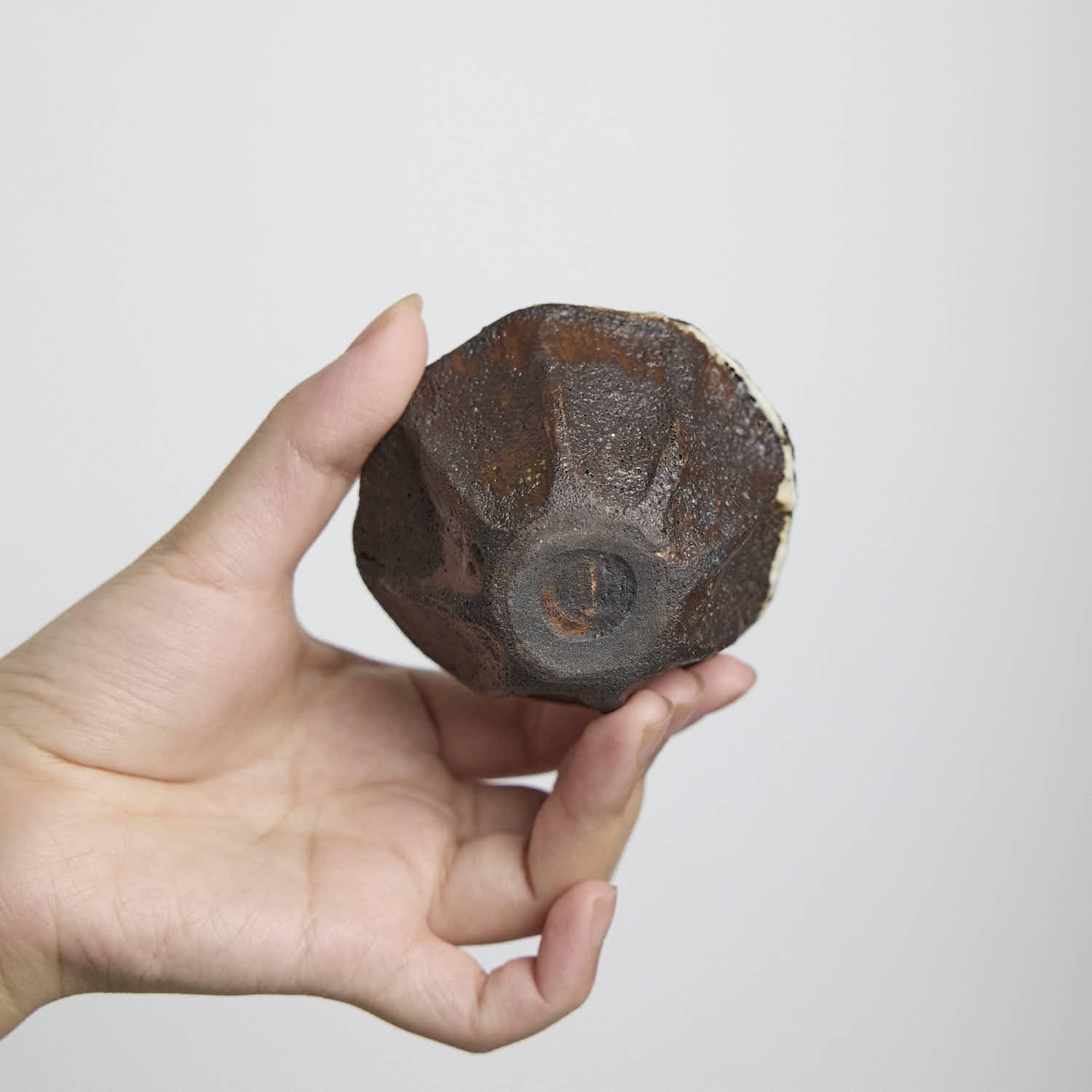 Handbuilt wood-fired clay cup with white slip finish, wabi-sabi style ceramic teacup showing natural ash glaze and irregular rim.