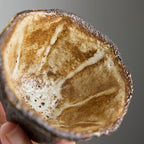 Handbuilt wood-fired clay cup with white slip finish, wabi-sabi style ceramic teacup showing natural ash glaze and irregular rim.
