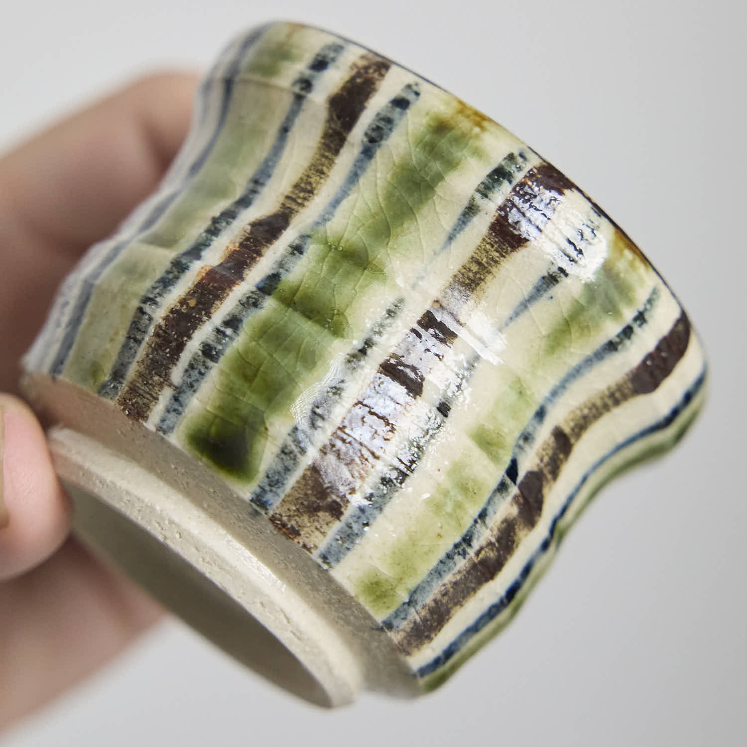 Close-up detail of the crackle glaze and striped pattern on a hand-built ceramic cup.