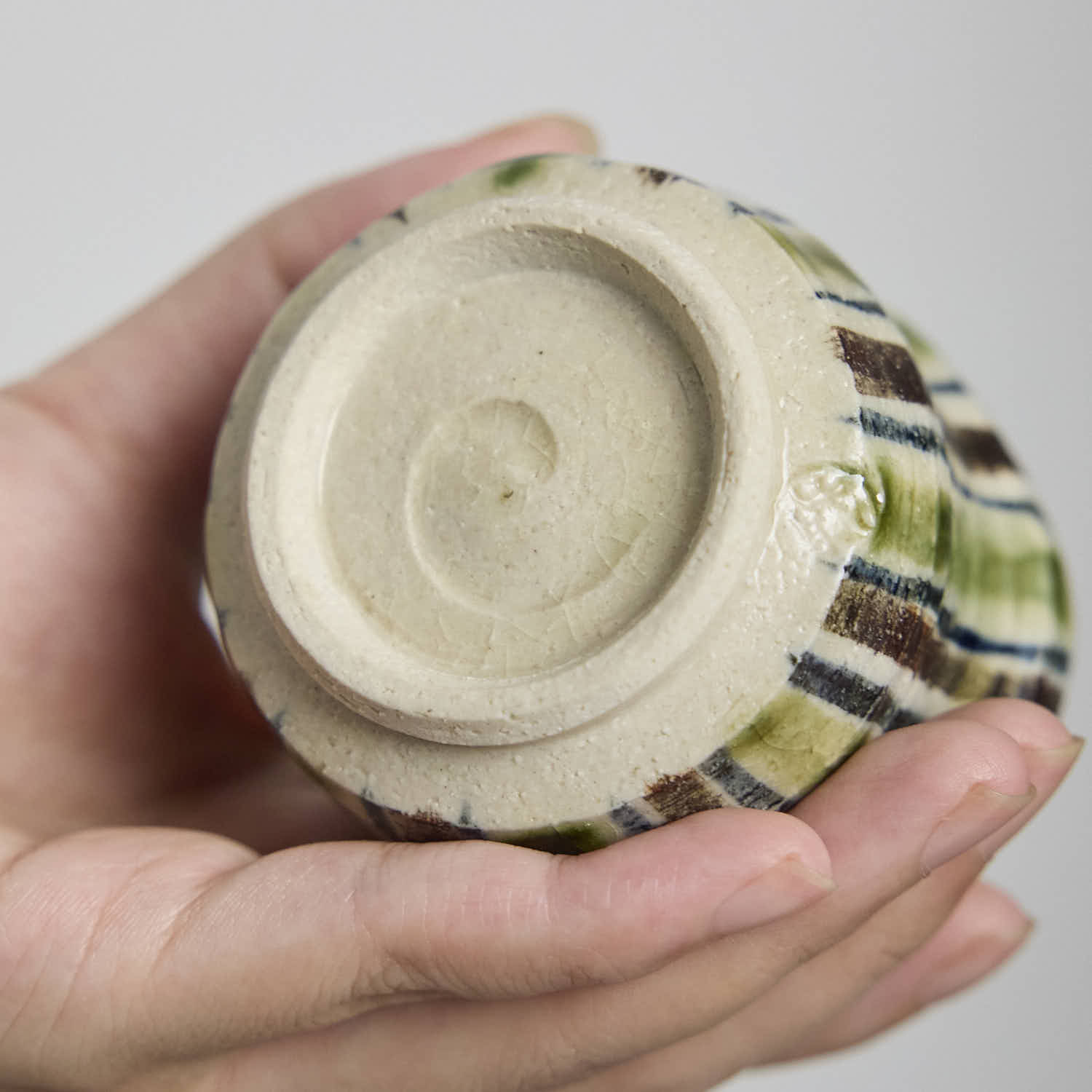 Close-up detail of the crackle glaze and striped pattern on a hand-built ceramic cup.