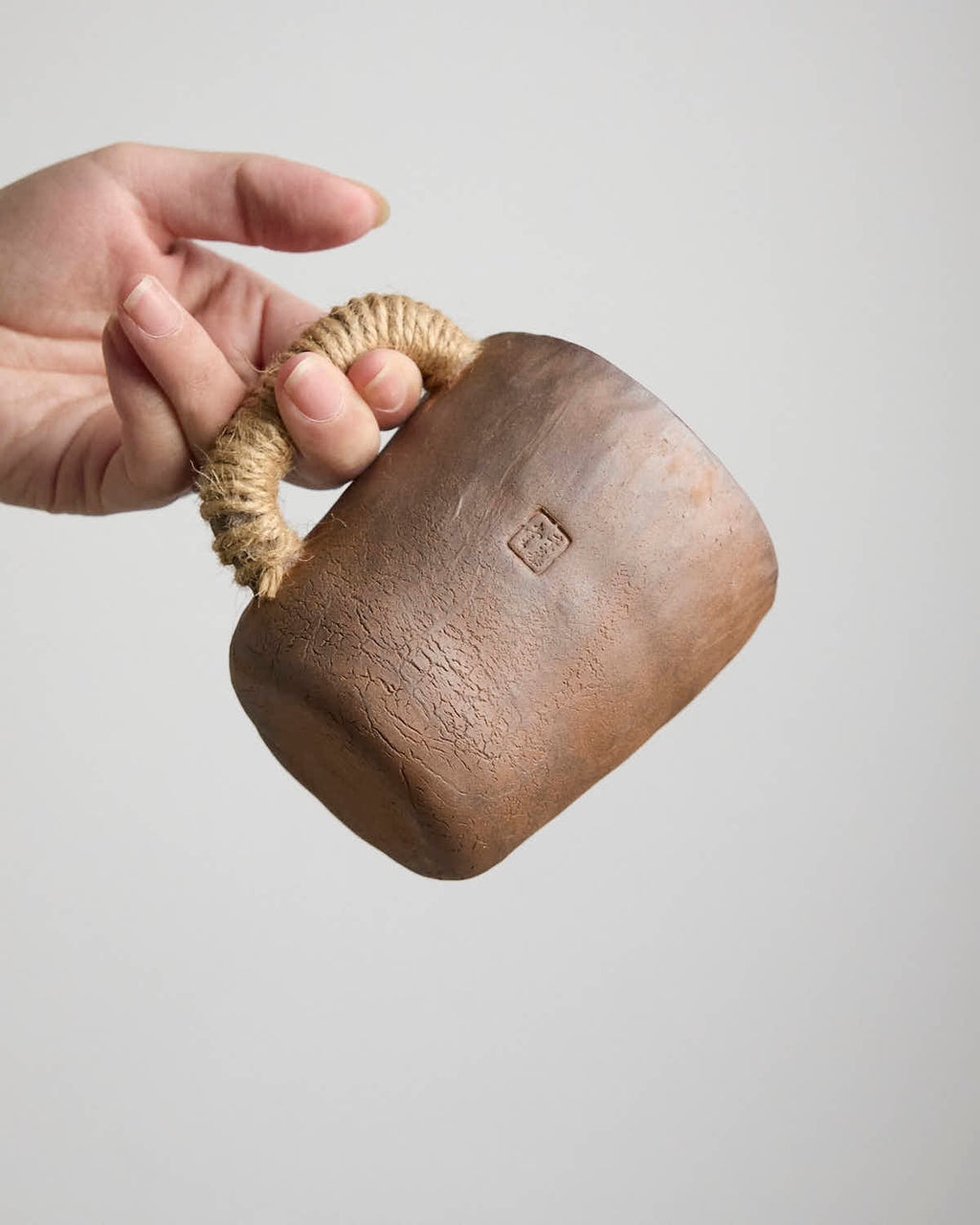 Hand-pinched rustic stoneware mug in earth tones with hemp-wrapped handle