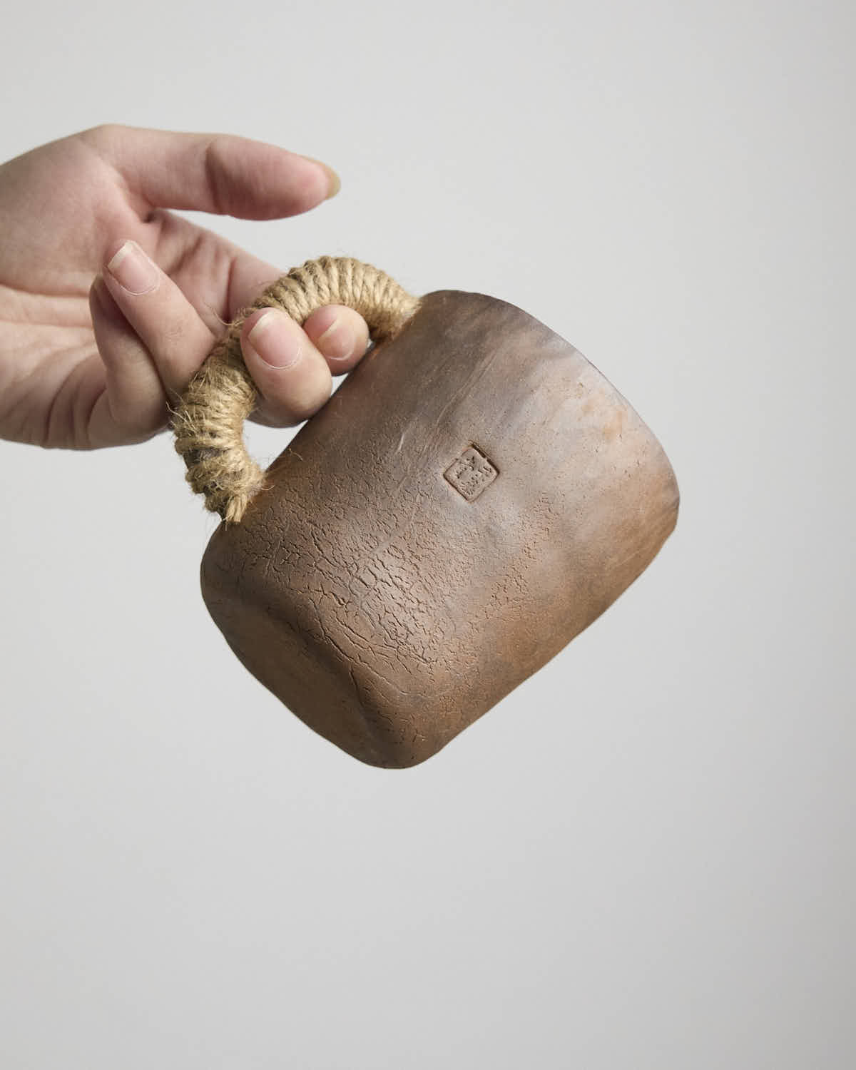 Hand-pinched rustic stoneware mug in earth tones with hemp-wrapped handle