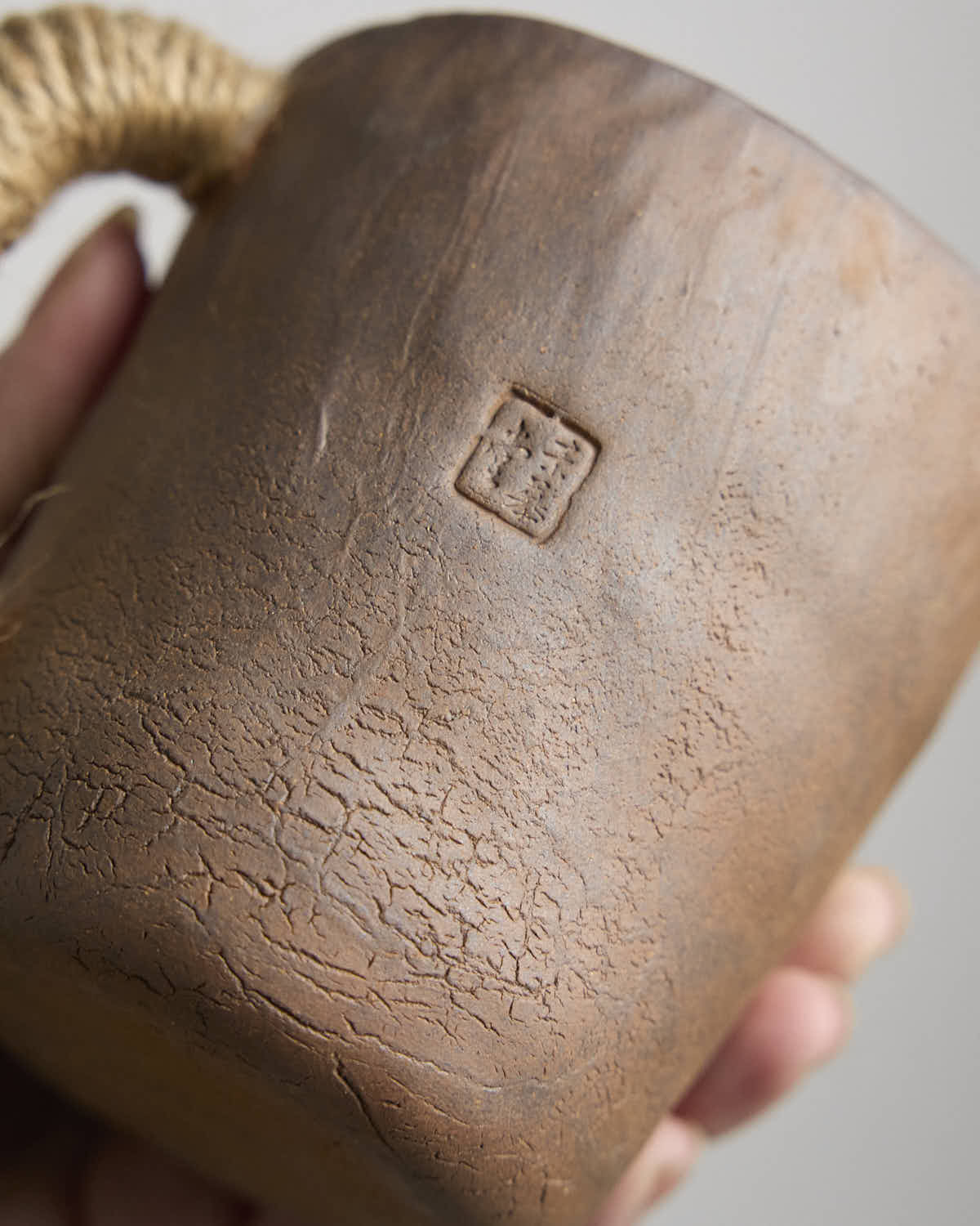 Hand-pinched rustic stoneware mug in earth tones with hemp-wrapped handle