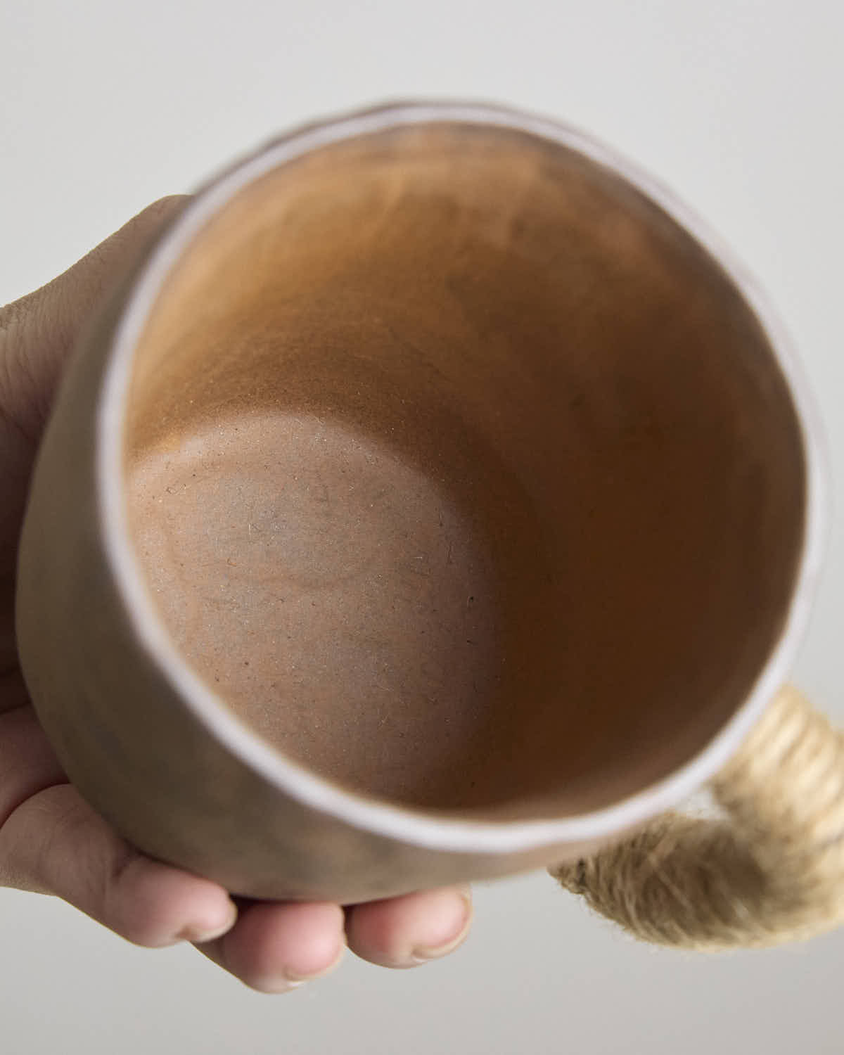 Hand-pinched rustic stoneware mug in earth tones with hemp-wrapped handle