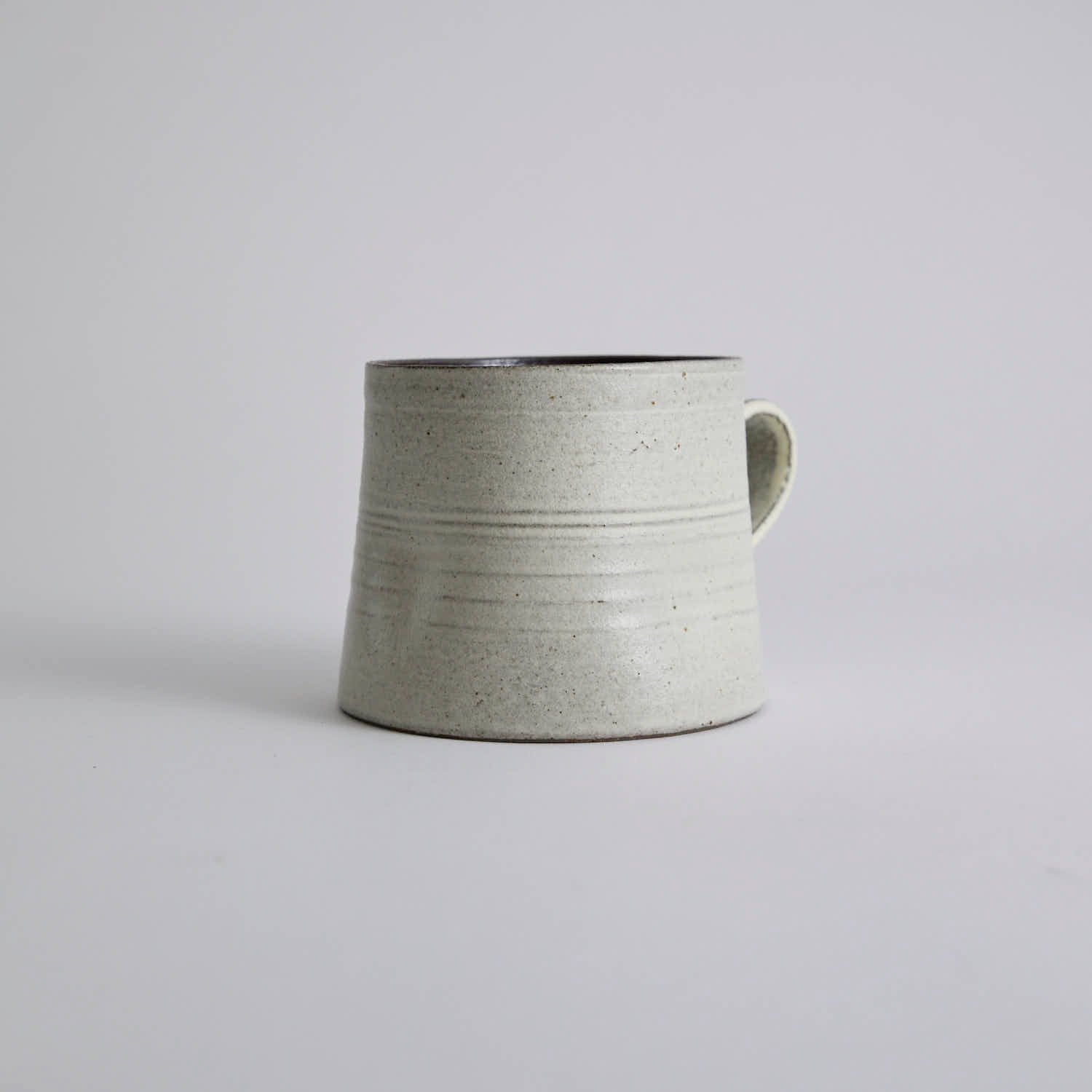Handcrafted kiln-varied coffee cup with square rim and natural speckled texture
