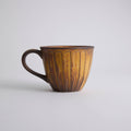 Rustic stoneware coffee cup and saucer set with textured surface inspired by Egyptian motifs
