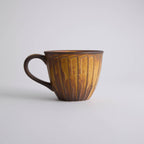 Rustic stoneware coffee cup and saucer set with textured surface inspired by Egyptian motifs