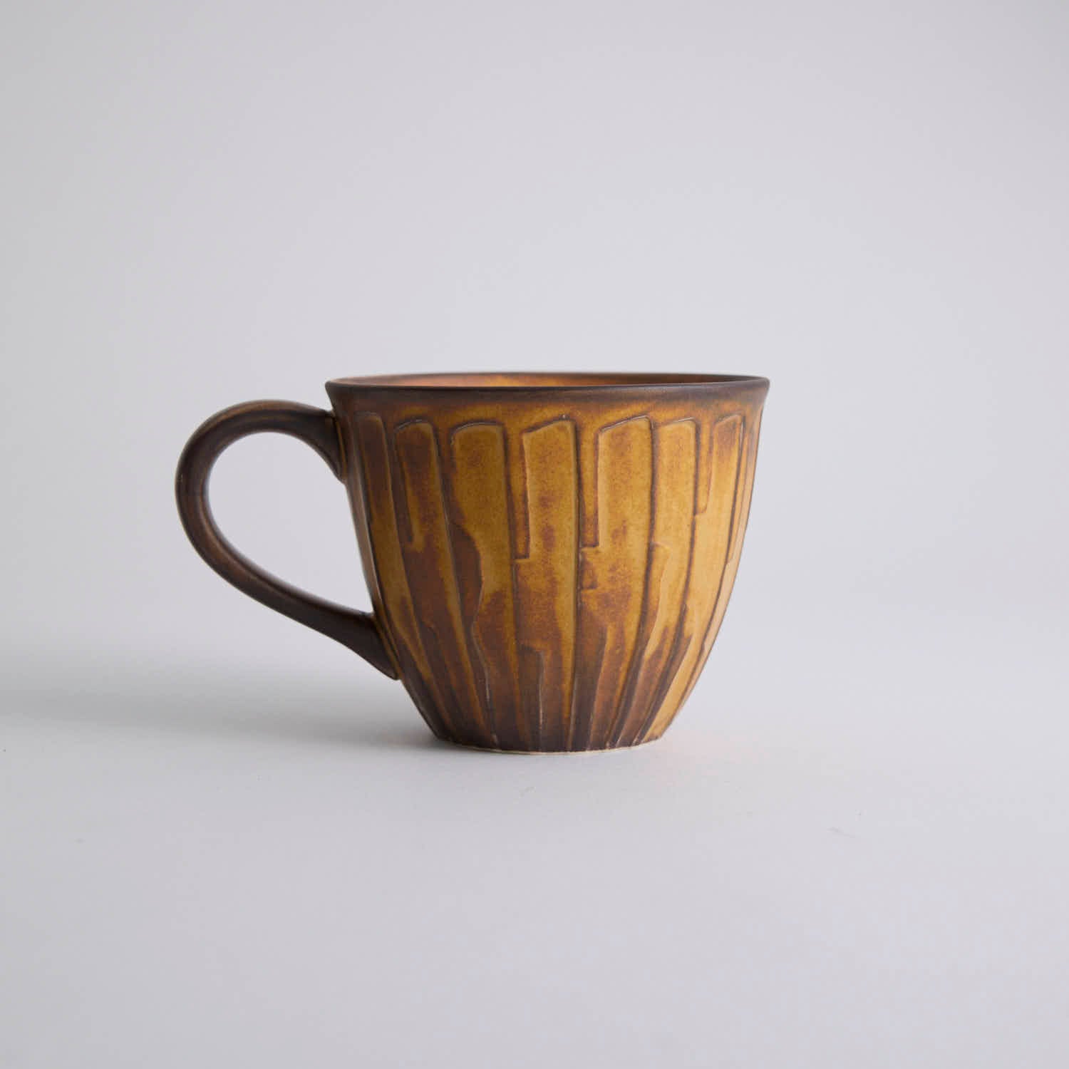 Rustic stoneware coffee cup and saucer set with textured surface inspired by Egyptian motifs
