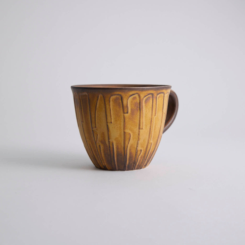 Rustic stoneware coffee cup and saucer set with textured surface inspired by Egyptian motifs