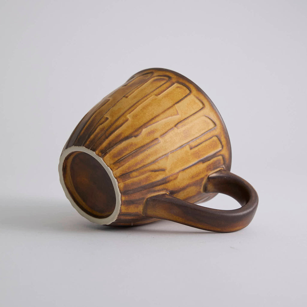 Rustic stoneware coffee cup and saucer set with textured surface inspired by Egyptian motifs