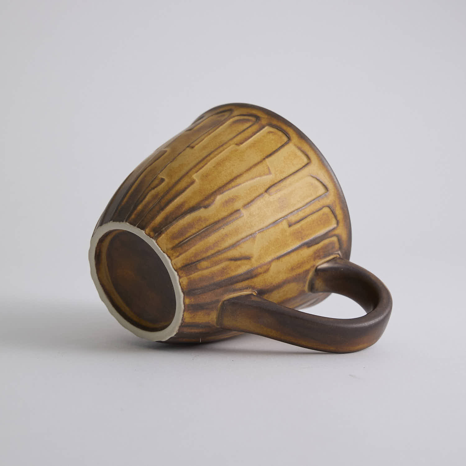 Rustic stoneware coffee cup and saucer set with textured surface inspired by Egyptian motifs