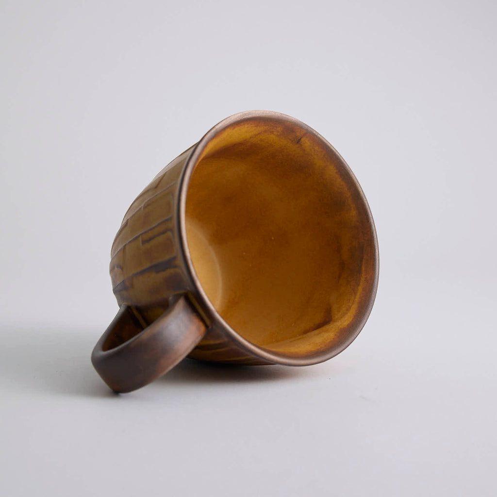 Rustic stoneware coffee cup and saucer set with textured surface inspired by Egyptian motifs