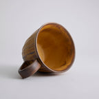 Rustic stoneware coffee cup and saucer set with textured surface inspired by Egyptian motifs