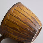 Rustic stoneware coffee cup and saucer set with textured surface inspired by Egyptian motifs