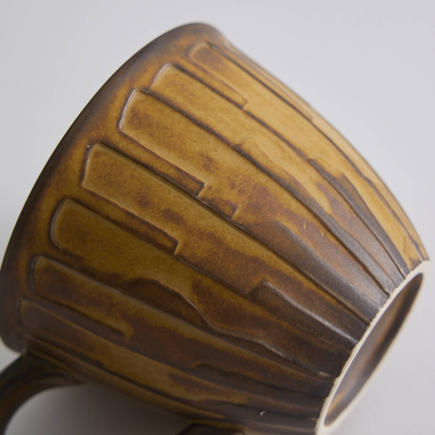 Rustic stoneware coffee cup and saucer set with textured surface inspired by Egyptian motifs