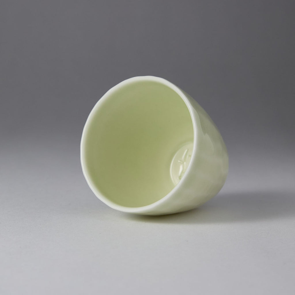 Ou Kiln hammered-texture celadon teacup with a tapered shape and soft jade-like glaze on a black background.